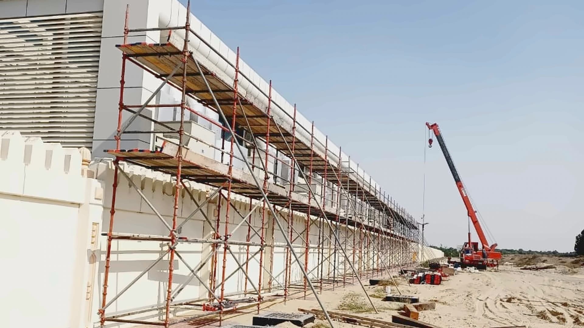 Access scaffolding along a building facade with a crane beside the site