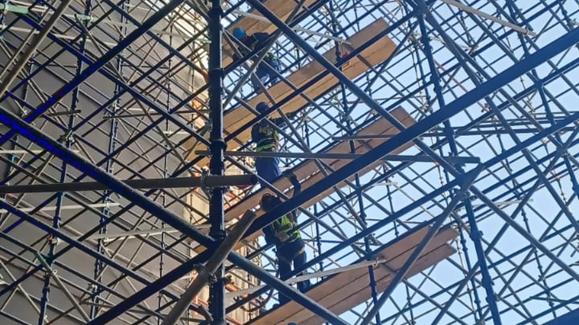 Workers on high-level scaffold platforms beside a building under construction