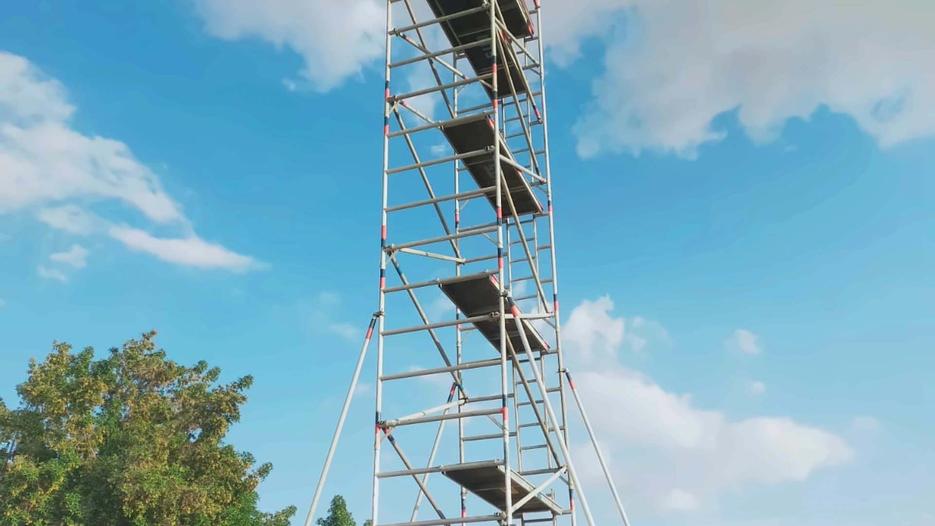 Freestanding scaffold tower with stabilising supports in an outdoor yard